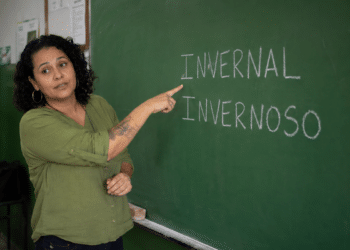 Professora em sala de aula apontando para lousa com as palavras invernal e invernoso escritas em giz.