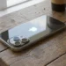 iPhone sobre mesa de madeira, ilustrando modelos compatíveis com o iOS 27.