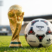Taça da Copa do Mundo ao lado de uma bola de futebol no gramado
