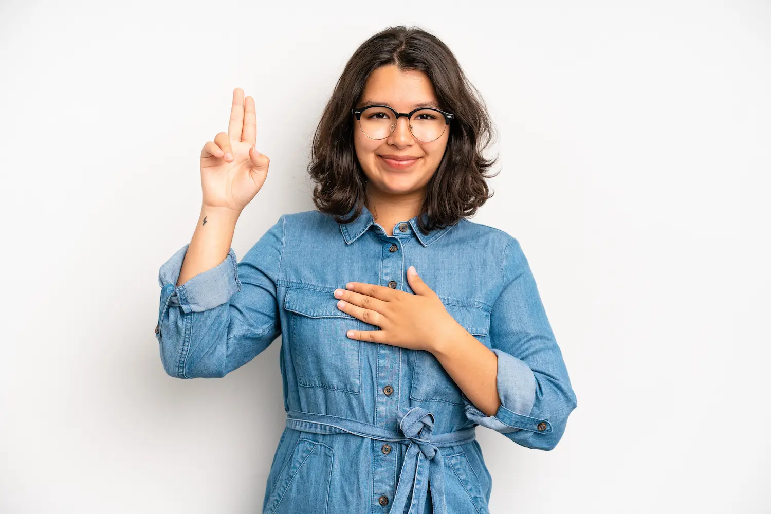 Profissional utilizando Libras em contexto educacional inclusivo Mulher realizando sinal em Libras com as mãos, representando comunicação inclusiva no ambiente educacional.