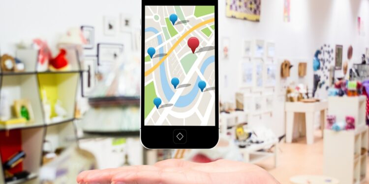 Mão segura celular exibindo mapa com vários marcadores de localização.