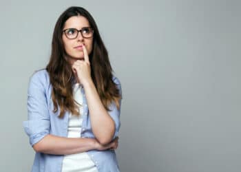 Mulher pensativa reflete sobre o plural de meio-fio e as formas erradas "meios-fio" e "meio-fios"