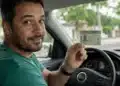 Motorista brasileiro mostrando a CNH dentro do carro, representando a satisfação com a renovação automática da carteira de motorista