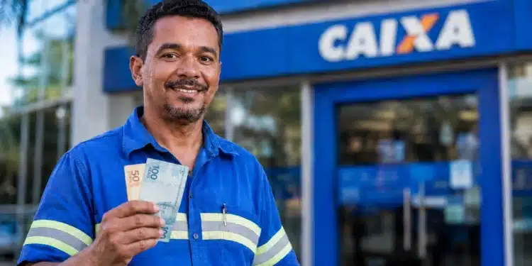 Trabalhador sorrindo segura cédulas de real em frente à Caixa, representando a liberação de até R$ 1.621 pela Caixa ou pelo Banco do Brasil.