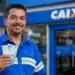Trabalhador sorrindo segura cédulas de real em frente à Caixa, representando a liberação de até R$ 1.621 pela Caixa ou pelo Banco do Brasil.
