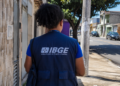Profissional com uniforme do IBGE em rua residencial durante atividade de campo