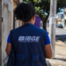 Profissional com uniforme do IBGE em rua residencial durante atividade de campo