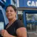 Mulher segura notas de reais em frente a caixa eletrônico da Caixa, representando o novo pagamento de R$ 6.220.