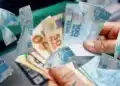 Pessoa segurando notas de real, ilustrando novo saque de R$ 6.220 liberado pela Caixa para quem tem direito ao valor.