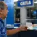 Idoso brasileiro recebendo cédulas de dinheiro em agência bancária, representando o pagamento do INSS nesta segunda-feira, 8 de junho.