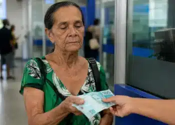 Mulher idosa recebendo pagamento do INSS em agência bancária brasileira