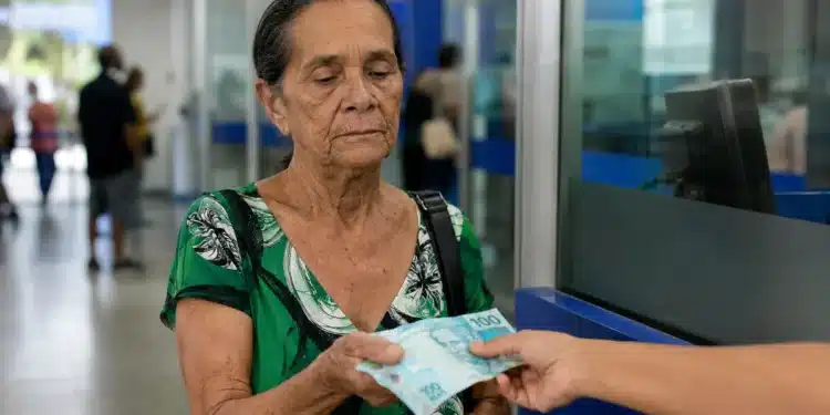 Mulher idosa recebendo pagamento do INSS em agência bancária brasileira