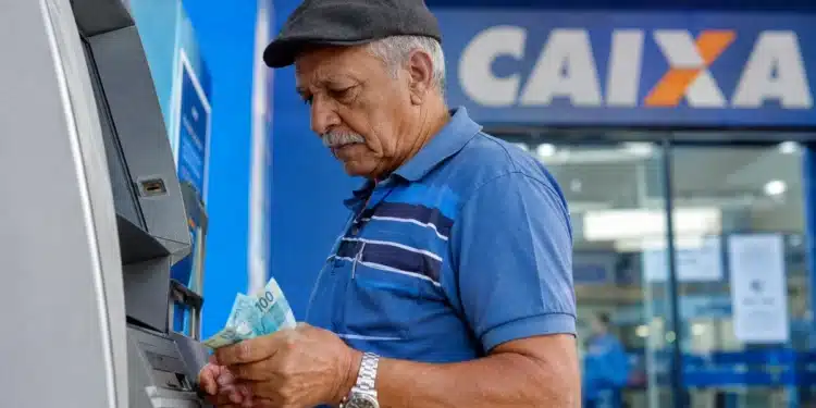 Beneficiário do INSS retira dinheiro em caixa eletrônico da Caixa, representando o pagamento desta sexta-feira, 26 de junho.