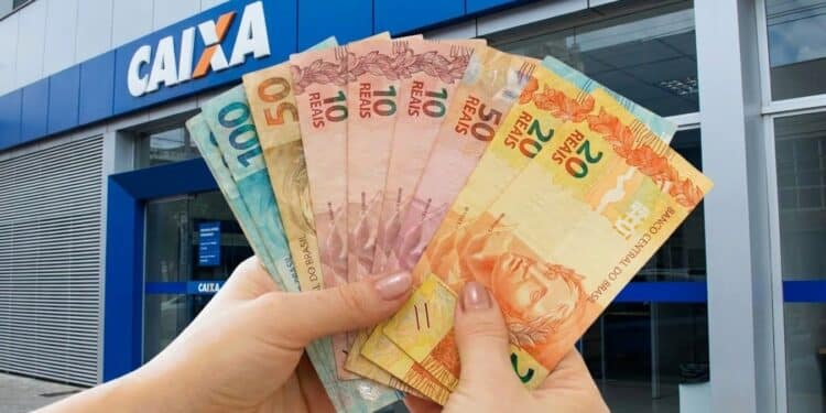 Mãos seguram cédulas diante de agência da Caixa, banco que paga os valores do Pé-de-Meia