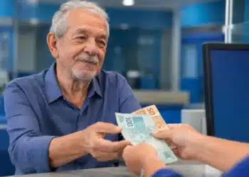 Idoso recebendo pagamento em agência do INSS, representando pagamentos no teto de R$ 8.475,55 liberados nesta semana.
