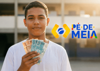 Estudante segura notas de R$ 50 e R$ 100 diante da escola, representando o pagamento do Pé-de-Meia