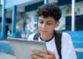 Estudante brasileiro em uniforme escolar olhando para um calendário, representando a consulta às datas de pagamento do programa em junho de 2026.
