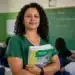 Professora brasileira em sala de aula pública segurando material didático, representando a valorização do piso salarial da educação básica.