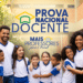 Educadores ao lado de alunos uniformizados em pátio escolar com a logomarca da Prova Nacional Docente em destaque.