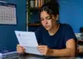 Jovem em ambiente doméstico analisando documento sobre resultados da PND 2026, representando a divulgação do resultado dos recursos sobre a isenção da taxa de inscrição.