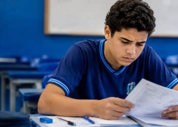 Candidato do Enem 2026 analisa uma folha em sala de aula, ilustrando a verificação do pedido de atendimento especializado dentro do prazo de recurso