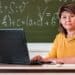 Professora ao computador em sala de aula representa as áreas avaliadas na Prova Nacional Docente 2026