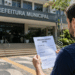 Homem lendo edital de processo seletivo em frente à Prefeitura Municipal em Santa Catarina.