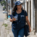 Agente do IBGE em trabalho de campo caminhando em rua urbana com prancheta.