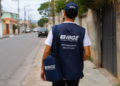 Agente do IBGE fardado caminha pela rua, representando seleção com mais de 1.400 vagas e inscrições abertas.