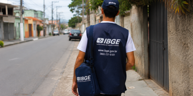 Agente do IBGE fardado caminha pela rua, representando seleção com mais de 1.400 vagas e inscrições abertas.