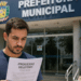Candidato lê edital de processo seletivo em frente à prefeitura municipal.