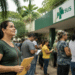 Pessoas aguardam atendimento em frente a unidade da Secretaria de Saúde com símbolo do SUS.