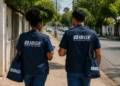 Dois agentes do IBGE caminhando em rua residencial durante trabalho de campo de pesquisa estatística.