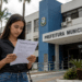 Mulher lendo edital de processo seletivo em frente ao prédio da Prefeitura Municipal.