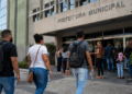 Pessoas em frente à prefeitura municipal aguardando atendimento em processo seletivo com vagas abertas.
