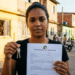Mulher segura chaves e um contrato do Minha Casa, Minha Vida - Aluguel Social em frente a casas de uma rua