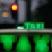 Taxi urbano iluminado à noite com letreiro verde “TAXI”, simbolizando o transporte por aplicativo e renovação de frota no programa Move Brasil.
