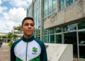 Jovem de agasalho esportivo do Brasil em frente a um prédio público