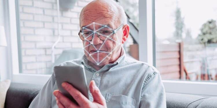 Idoso de óculos realiza reconhecimento facial pelo celular com malha de biometria sobre o rosto