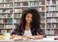 Estudante concentrada organizando estudos para o Enem 2026 em ambiente de biblioteca.