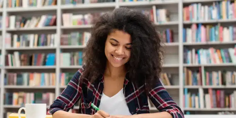 Estudante concentrada organizando estudos para o Enem 2026 em ambiente de biblioteca.