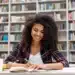 Estudante concentrada organizando estudos para o Enem 2026 em ambiente de biblioteca.