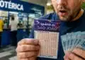 Apostador segurando bilhete da Quina de São João e cédulas de real em lotérica brasileira, representando o sorteio que será realizado em 28/06.