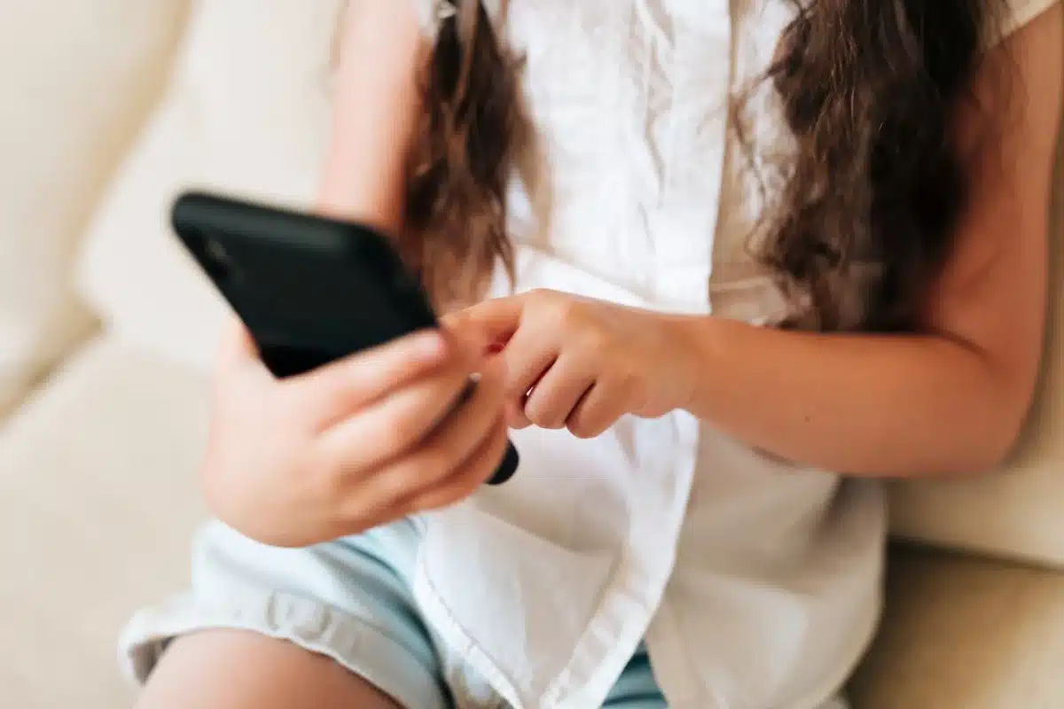 Uso de redes sociais por menores - Restrições dos países Adolescente segurando smartphone, representando as restrições de alguns países ao uso de redes sociais por menores.