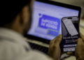 Contribuinte usa celular e notebook para acompanhar a restituição do Imposto de Renda.