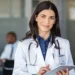 Médica com jaleco e tablet em ambiente hospitalar, representando as inscrições abertas para a primeira etapa do Revalida 2026/2.