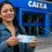 Mulher segurando notas de dinheiro em frente a uma agência da Caixa, representando o saque de R$ 6.220.