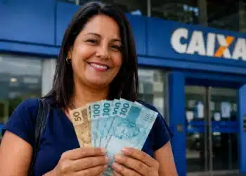 Mulher sorrindo com notas de reais em frente a uma agência da Caixa, representando o saque de R$ 6.220.