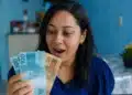 Mulher segurando notas de dinheiro, representando o saque do FGTS de até R$ 6.220 para moradores da BA, RJ e MG.