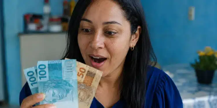 Mulher segurando notas de dinheiro, representando o saque do FGTS de até R$ 6.220 para moradores da BA, RJ e MG.
